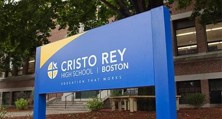 克里斯托·雷伊学校外的蓝色标牌上写着白字。波士顿，Cristo Rey高中——有效的教育。图片来源:Cristo Rey高中