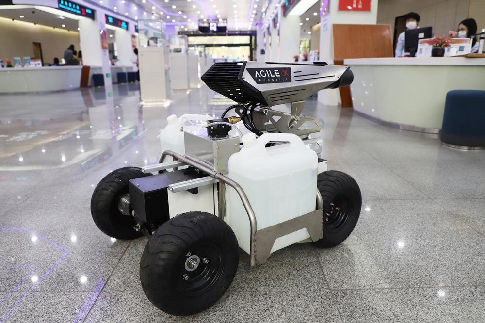 一个带着两罐消毒剂的消毒机器人进入商业空间。它有四个轮子和一个喷水装置。